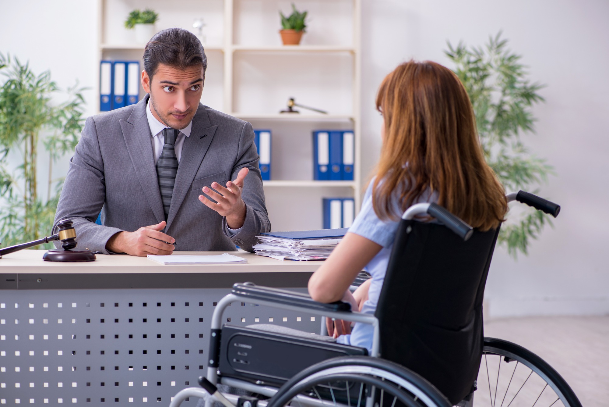A lawyer discusses a case with a woman in a wheelchair during a consultation